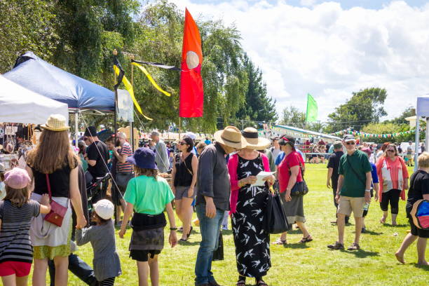 Crowd attending an outdoor event with tents and flags.