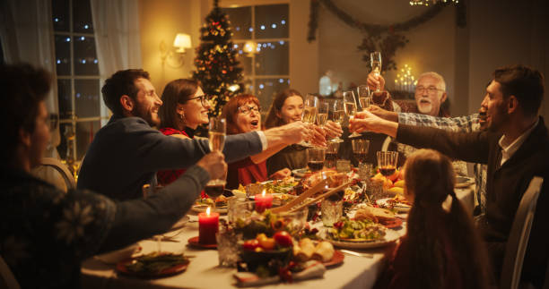 Group of people toasting with champagne at a festive Christmas dinner.