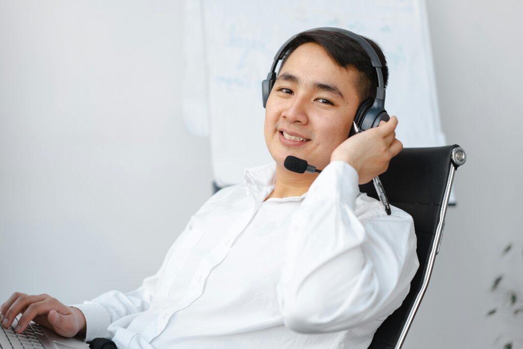 Man in headset working at laptop, with white background.